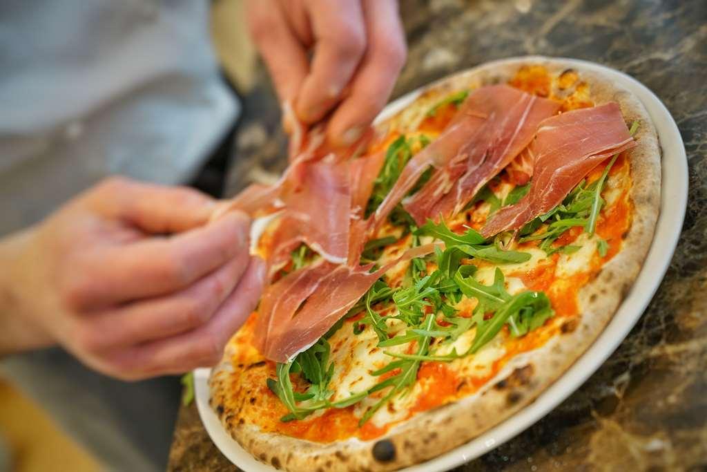 Vila Vita Rosenpark Marburg Exteriér fotografie Pizza being topped with prosciutto